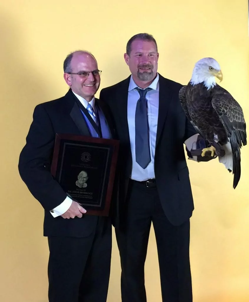 Dr. Stephen Beveridge receiving a top dentist award and holding an eagle