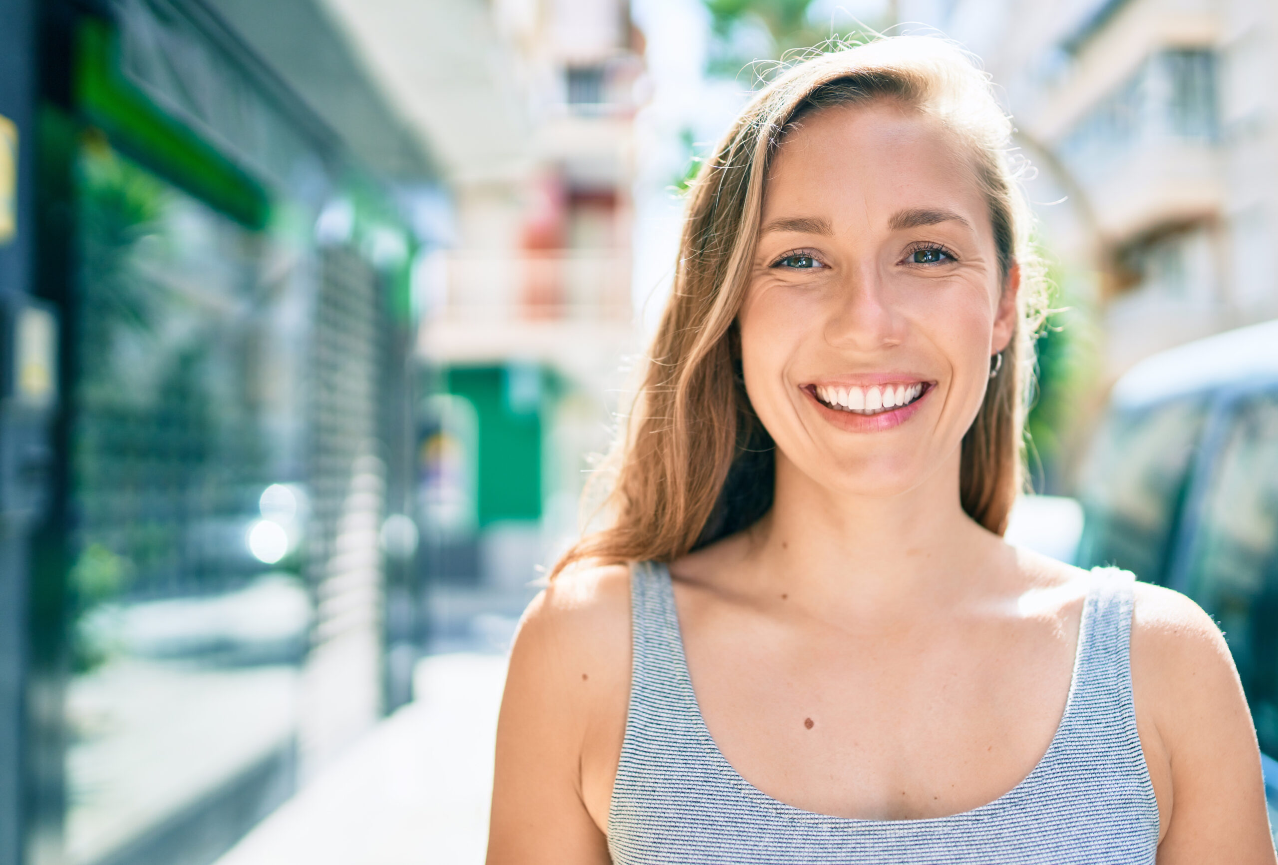 closeup of a young woman on a city street, perfect white smile
