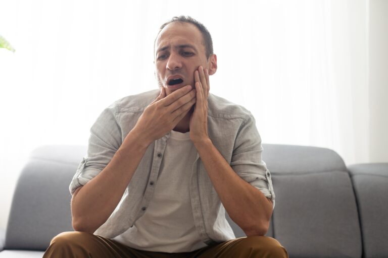 man on a couch suffering from tooth pain