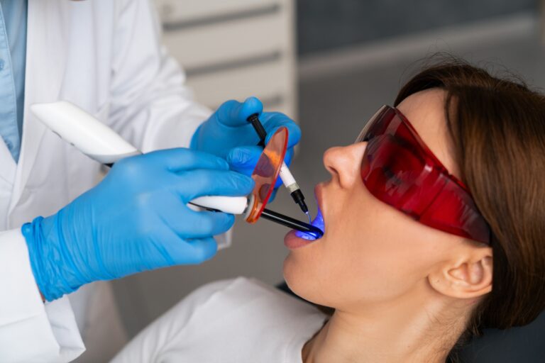 dentist in blue gloves treating a woman with dental laser