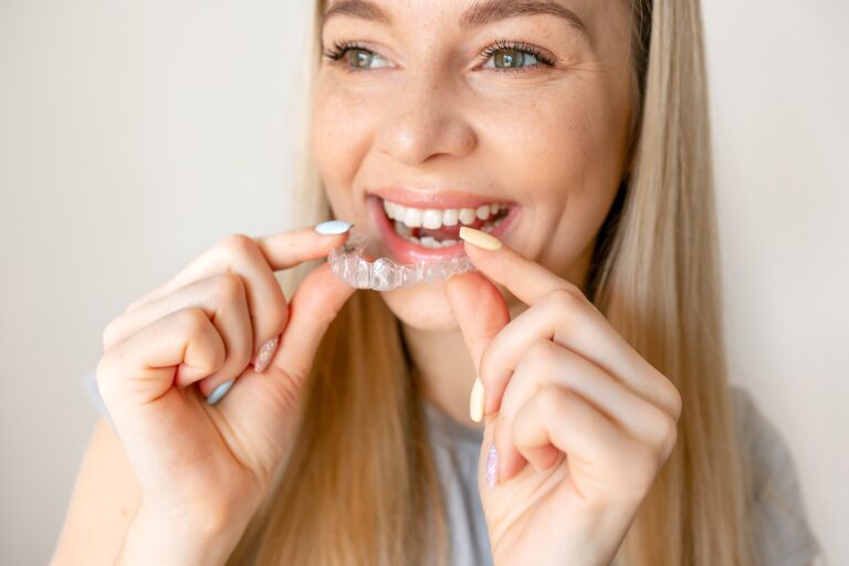 Young woman holding an invisible aligner. Dental health, beautiful smile