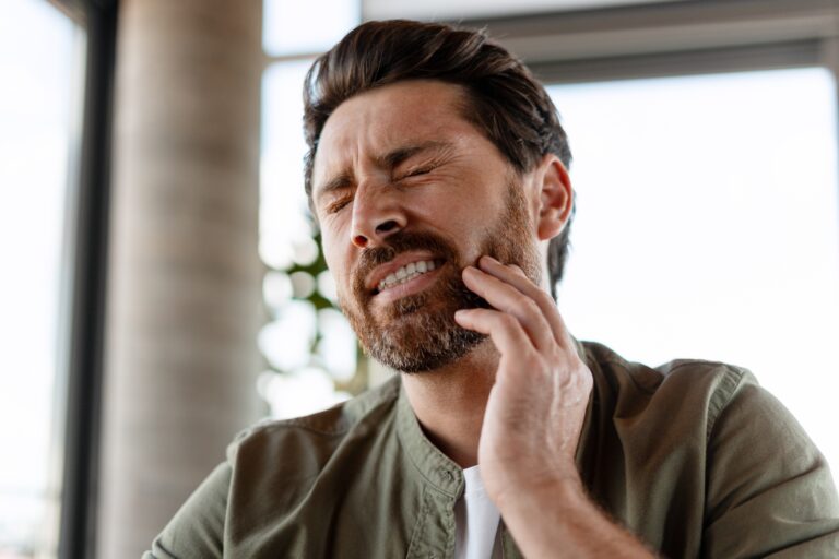 bearded man with severe tooth pain, hand on jaw